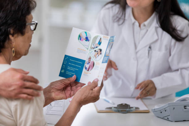 Senior woman reads a pharmacy brochure while picking up a prescription. She is reading about the pharmacy's services.